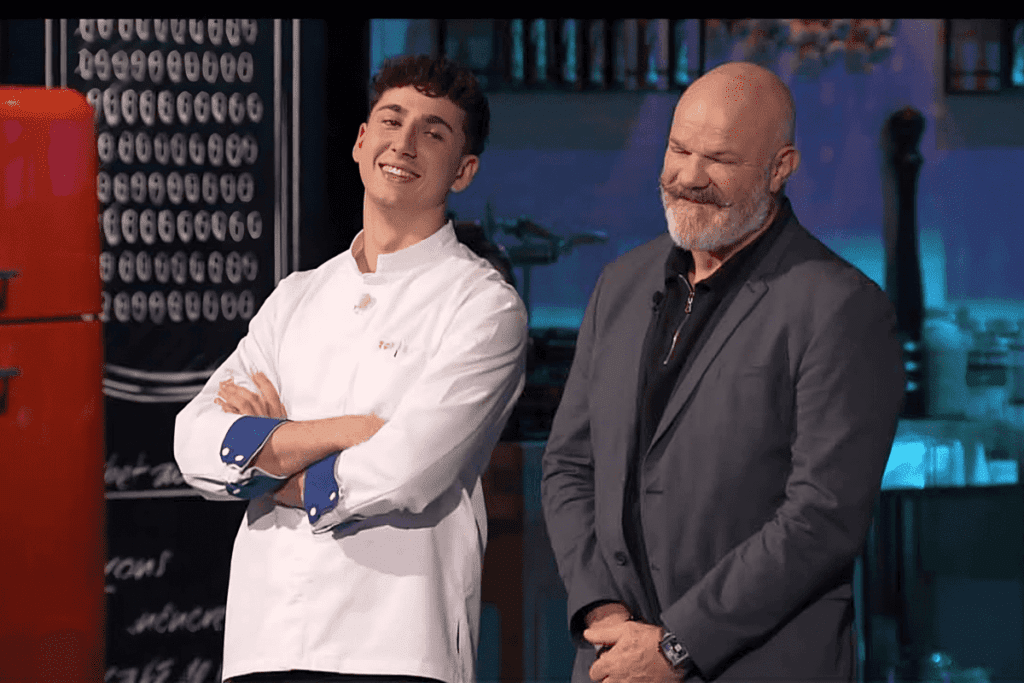 Hugo de Top Chef 2023, souriant aux côtés du célèbre chef français Philippe Etchebest, dans une cuisine, prêt pour la finale.