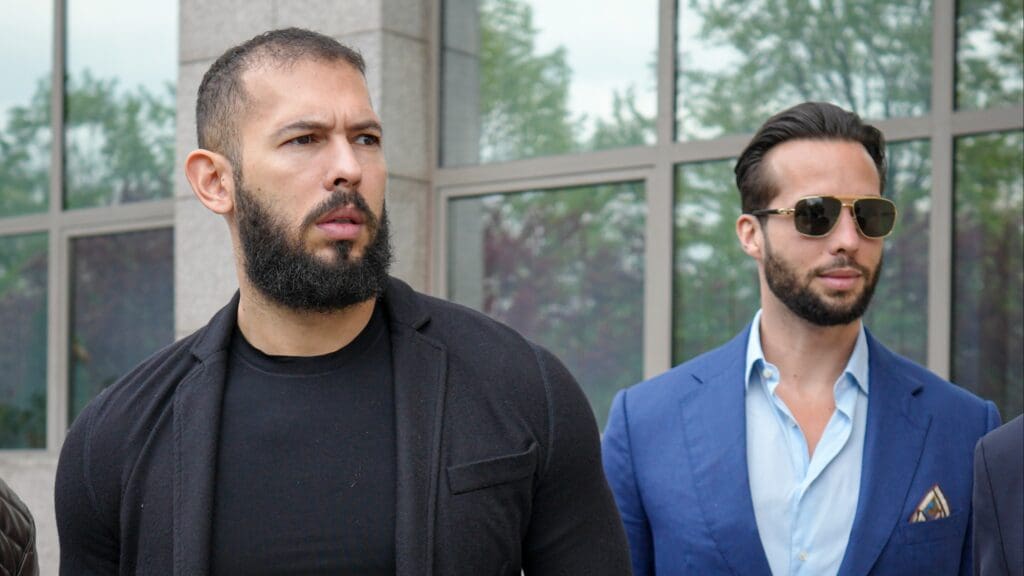 une photo d'Andrew Tate et de son frère Tristan Tate devant le tribunal de Roumanie après avoir été accusés de viol et de traite d'êtres humains