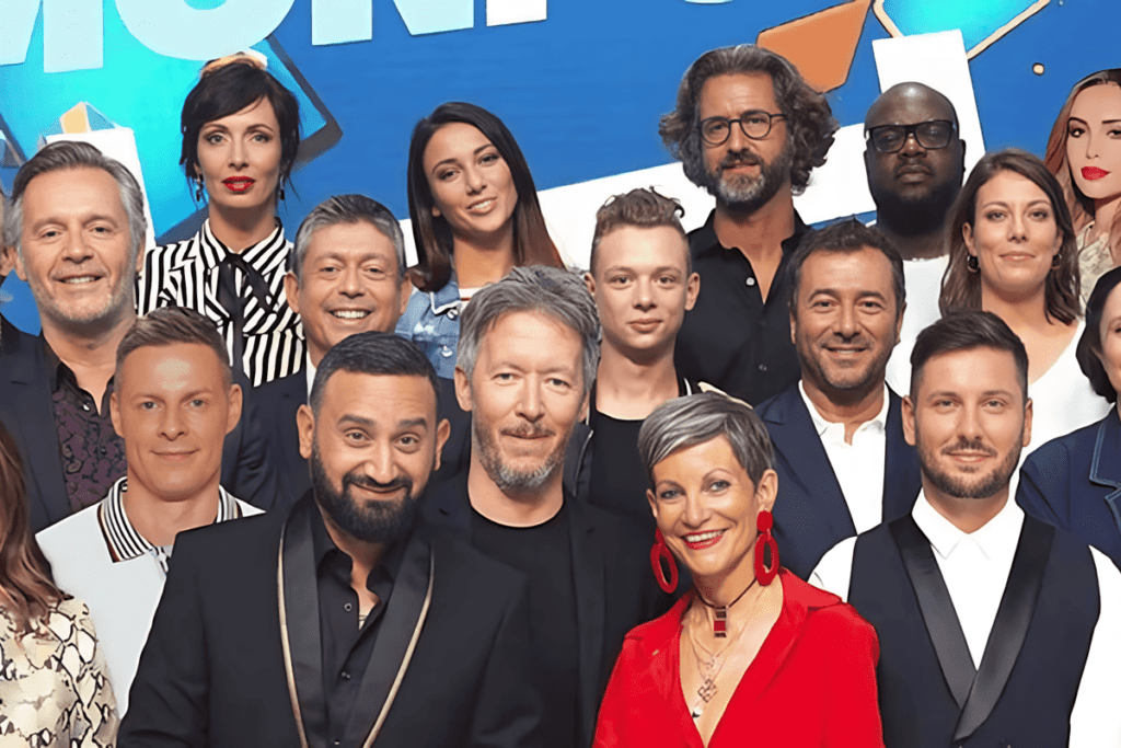 Cyril Hanouna, vêtu d'un costume noir et or, sourit à la caméra avec toute l'équipe de TPMP en arrière-plan dans leur studio télévisé mais sans les nouvelles recrues de TPMP